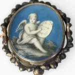 Grisaille cupid on a blue ground, in a beaded silver mount.