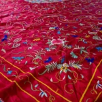 Deep red silk with a central medallion and multicoloured fringe.