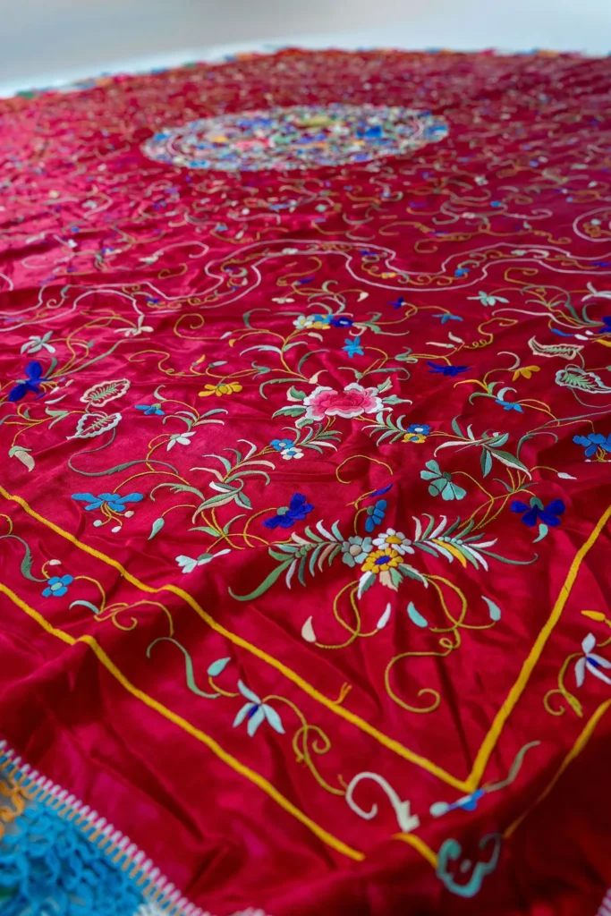 Deep red silk with a central medallion and multicoloured fringe.