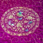 Violet silk embroidered in silver thread with birds and flowers.