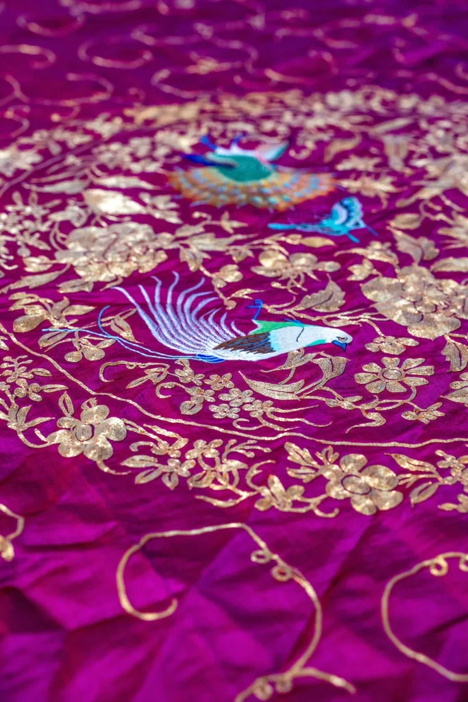 Violet silk embroidered in silver thread with birds and flowers.