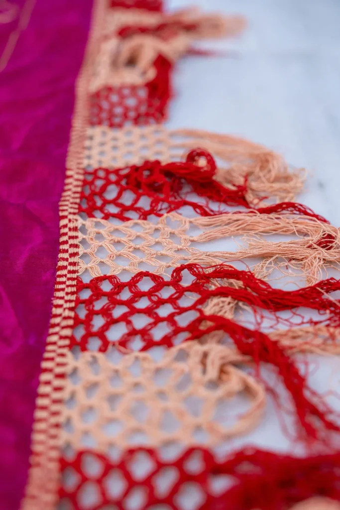 Magenta silk with white and silver floral work and a long fringe.
