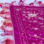 Magenta silk with white and silver floral work and a long fringe.