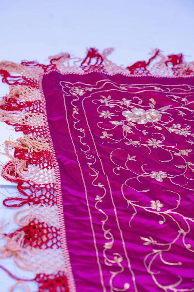 Magenta silk with white and silver floral work and a long fringe.