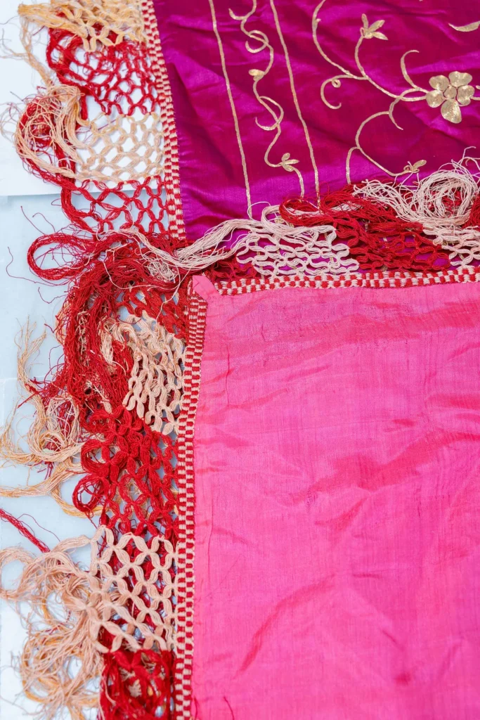 Magenta silk with white and silver floral work and a long fringe.